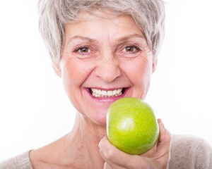 Smiling older woman holding green apple