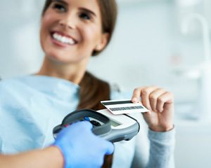 Smiling patient paying for treatment with credit card