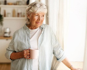 Senior woman looking out window while drinking tea