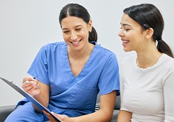 Dental assistant showing patient forms on clipboard