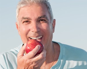 Smiling older man holding red apple