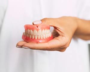 person in white lab coat holding dentures in Milwaukee