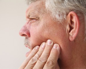 Closeup of man touching his cheek worried about dental implant failure