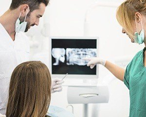 Dentist and patient looking at dental x-rays on computer