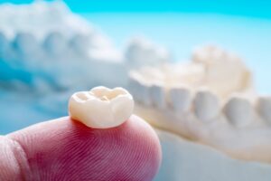 Finger balancing a dental crown. 