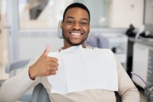Man smiling and holding up a thumbs ups