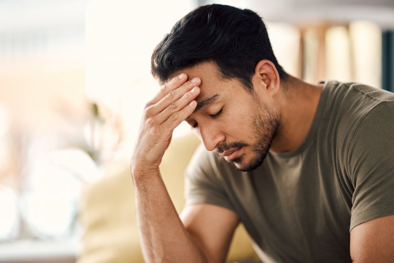 A tired and stressed man holding his head and closing his eyes