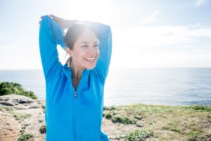 woman stretching and smiling on the beach